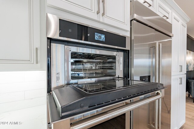 kitchen with sink, appliances with stainless steel finishes, light hardwood / wood-style flooring, white cabinetry, and island exhaust hood