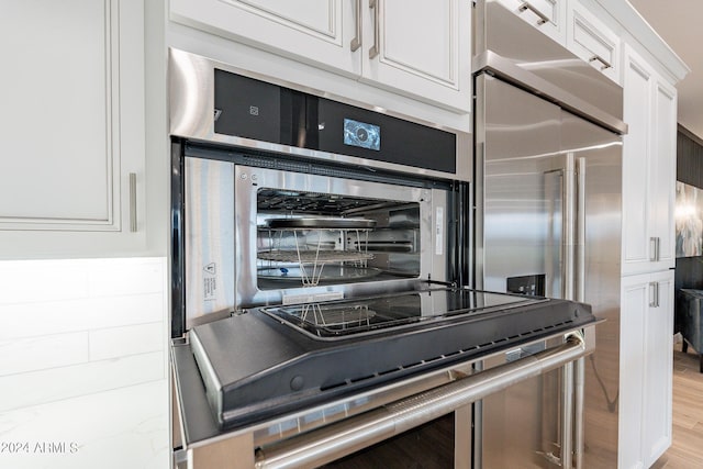 kitchen featuring light wood-type flooring, light stone counters, white cabinets, and high quality fridge