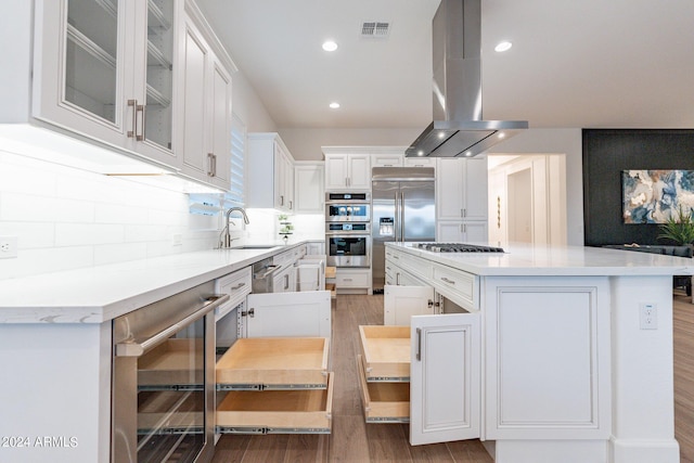 kitchen with white cabinets, island range hood, a kitchen island, sink, and wine cooler