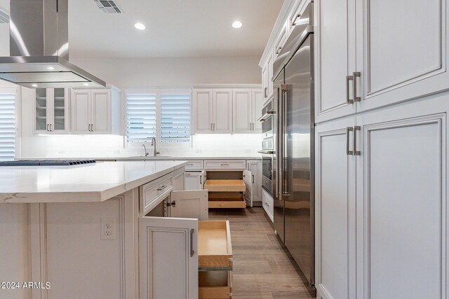 kitchen with backsplash, beverage cooler, hardwood / wood-style floors, island range hood, and sink