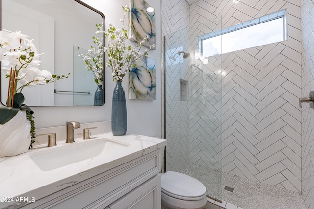 bathroom with tiled shower, toilet, and vanity