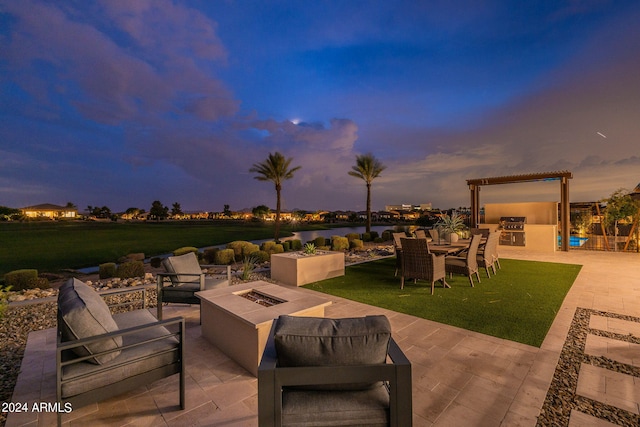 patio terrace at dusk with an outdoor living space with a fire pit and area for grilling