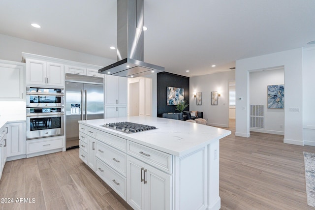 kitchen featuring white cabinetry, light wood-type flooring, stainless steel appliances, light stone counters, and island exhaust hood