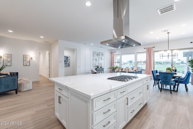 kitchen featuring island exhaust hood, appliances with stainless steel finishes, light stone countertops, and light hardwood / wood-style floors