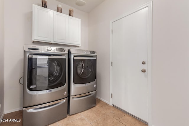 clothes washing area with cabinets, separate washer and dryer, and light tile patterned floors