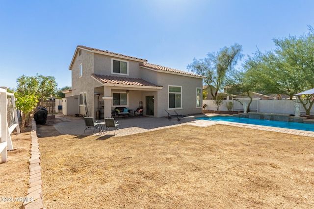 rear view of property with a fenced in pool and a patio area