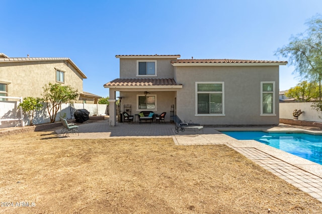 rear view of property with a fenced in pool, a patio area, and ceiling fan