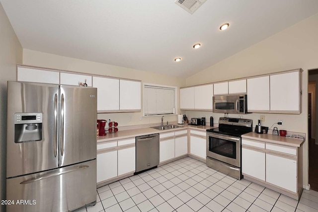 kitchen with sink, vaulted ceiling, light tile patterned floors, appliances with stainless steel finishes, and white cabinetry