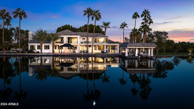 back house at dusk featuring a water view and a balcony