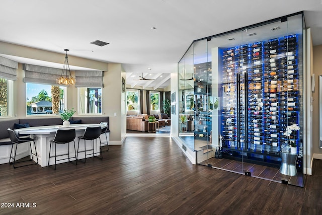 wine room with an inviting chandelier, a wealth of natural light, and dark wood-type flooring