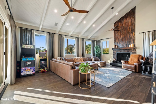 living room featuring ceiling fan, beam ceiling, hardwood / wood-style flooring, high vaulted ceiling, and a stone fireplace