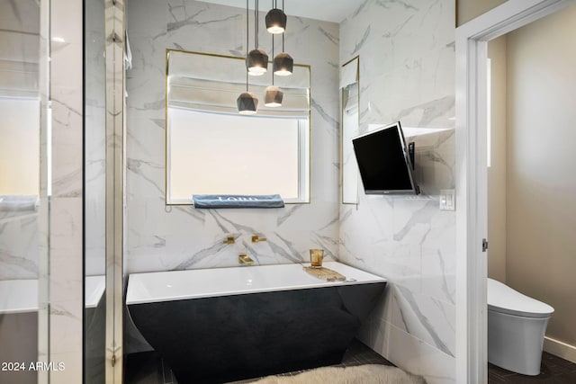 bathroom with a bath, toilet, and tile walls