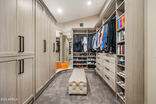 spacious closet with dark carpet and lofted ceiling