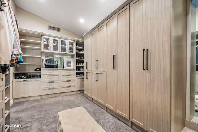 walk in closet with light carpet and vaulted ceiling