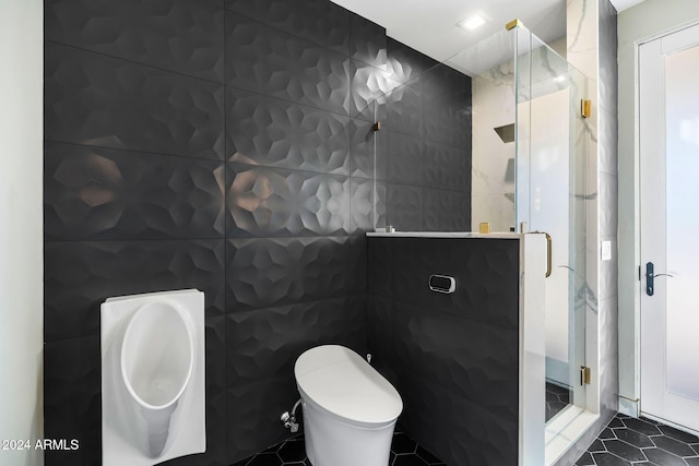 bathroom with tile patterned flooring, toilet, a shower with door, and tile walls