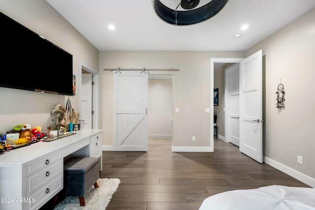 bedroom featuring a barn door and dark wood-type flooring