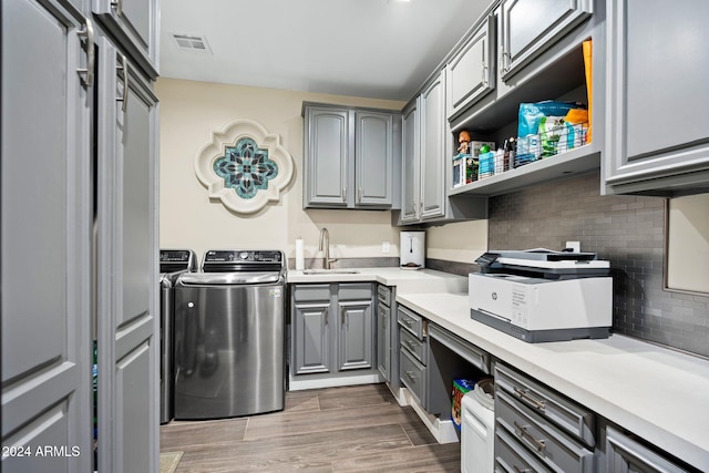 washroom featuring hardwood / wood-style floors, cabinets, sink, and washing machine and clothes dryer