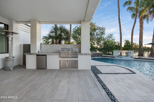 view of swimming pool featuring pool water feature, a patio, a grill, and exterior kitchen