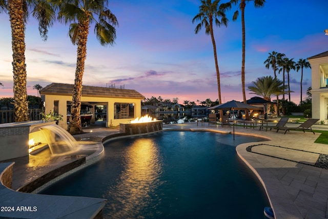 pool at dusk featuring a gazebo, pool water feature, and a patio