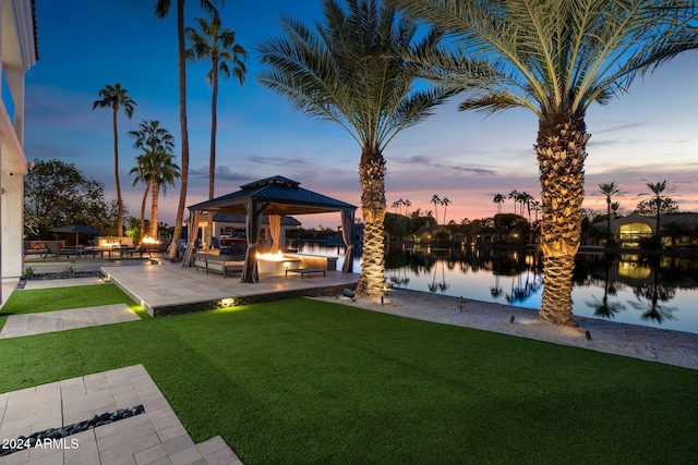 yard at dusk featuring a water view