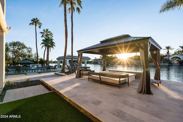 view of patio with a gazebo, a water view, and a dock