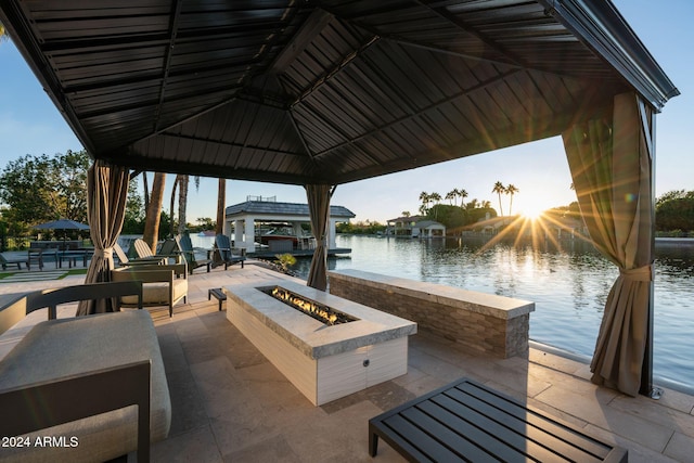 view of patio featuring a gazebo, a boat dock, a water view, and a fire pit