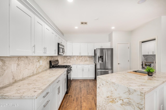 1492 E Westchester Dr, Chandler, AZ 85249 - kitchen with appliances with stainless steel finishes, a sink, wood finished floors, white cabinets, and decorative backsplash