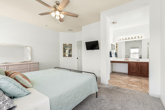 bedroom with ceiling fan, light colored carpet, ensuite bathroom, and sink