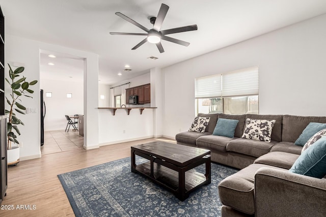 living room with light hardwood / wood-style floors and ceiling fan