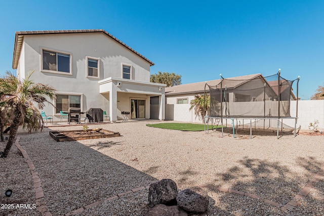 back of property with a trampoline and a patio