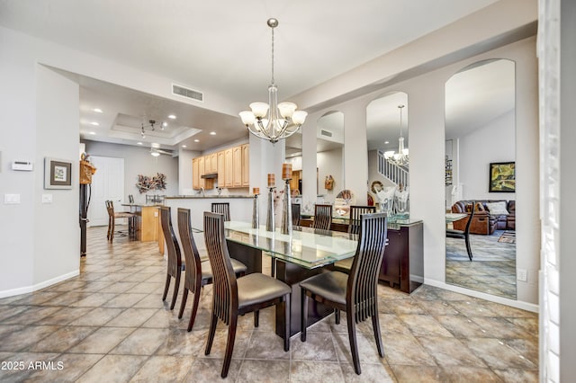 dining area featuring a chandelier and a raised ceiling