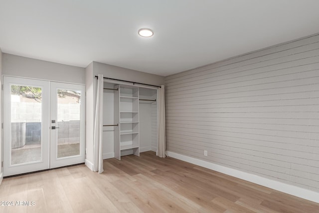 unfurnished bedroom featuring access to exterior, french doors, light wood-type flooring, and baseboards