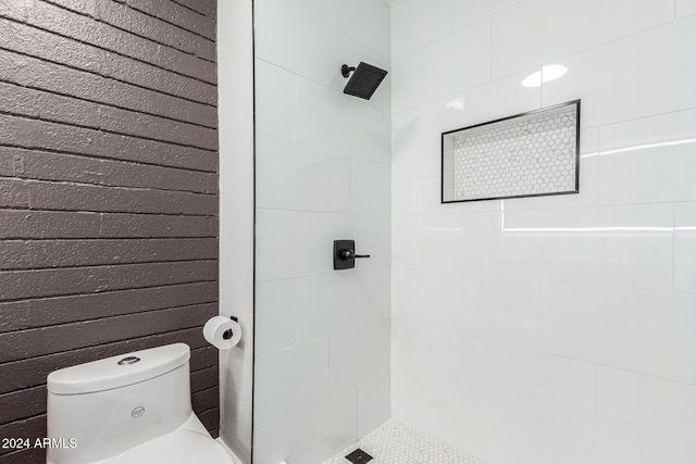 bathroom featuring tiled shower and toilet