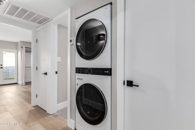 laundry area featuring visible vents, stacked washer and clothes dryer, light wood-style flooring, and laundry area