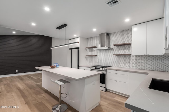 kitchen featuring visible vents, open shelves, a kitchen island, appliances with stainless steel finishes, and wall chimney exhaust hood