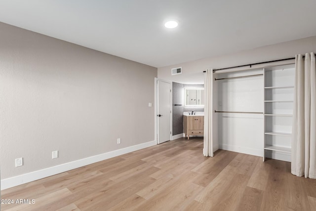 unfurnished bedroom with visible vents, baseboards, light wood-style floors, and a sink