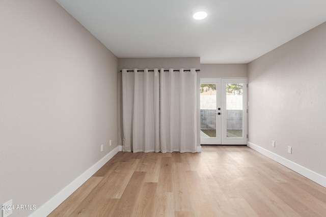 empty room featuring french doors, light wood-style floors, and baseboards