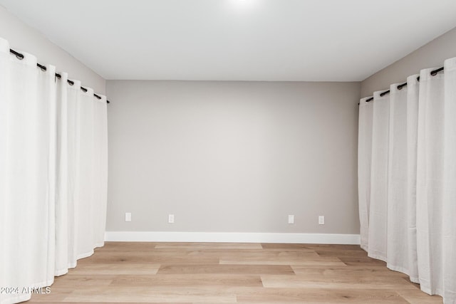 unfurnished room featuring baseboards and light wood-type flooring