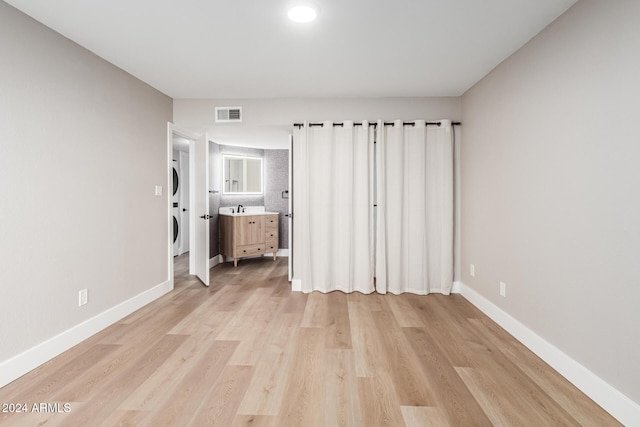 unfurnished bedroom with a sink, visible vents, baseboards, and light wood finished floors