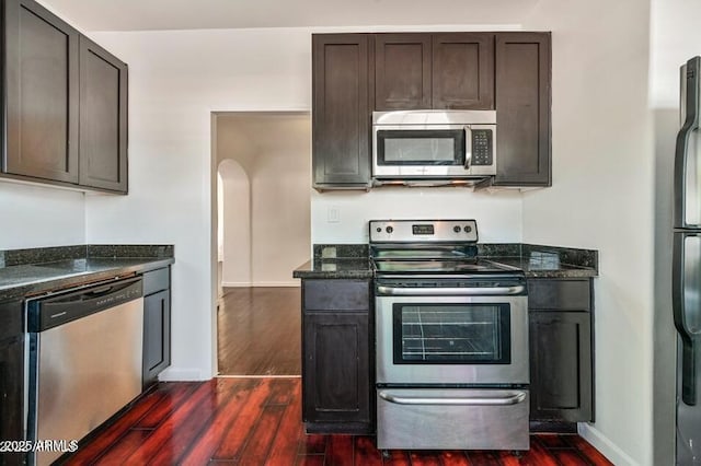3949 E Earll Dr, Phoenix, AZ 85018 - kitchen with appliances with stainless steel finishes, dark wood-type flooring, arched walkways, and dark stone counters