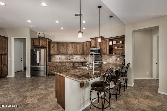 kitchen with stainless steel appliances, sink, decorative light fixtures, dark stone countertops, and backsplash