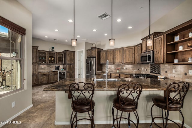 kitchen featuring sink, stainless steel appliances, backsplash, hanging light fixtures, and dark brown cabinetry