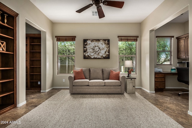 living room featuring ceiling fan and built in desk