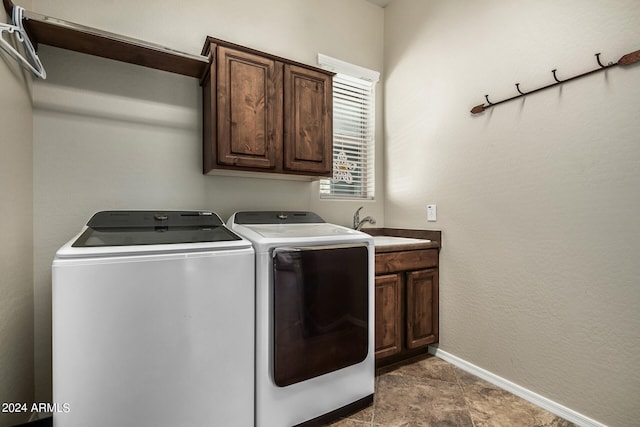 clothes washing area featuring sink, washing machine and dryer, and cabinets