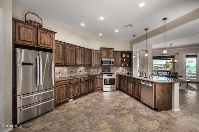 kitchen featuring hanging light fixtures, sink, appliances with stainless steel finishes, dark stone countertops, and dark brown cabinetry