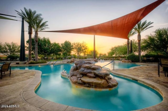 pool at dusk featuring a patio area