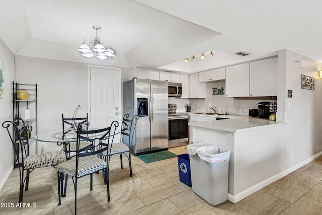 7520 E Papago Dr, Scottsdale, AZ 85257 - kitchen with light countertops, visible vents, stainless steel appliances, a tray ceiling, and a notable chandelier