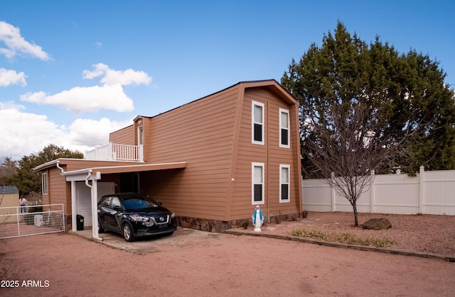 view of side of home featuring driveway, fence, and a carport