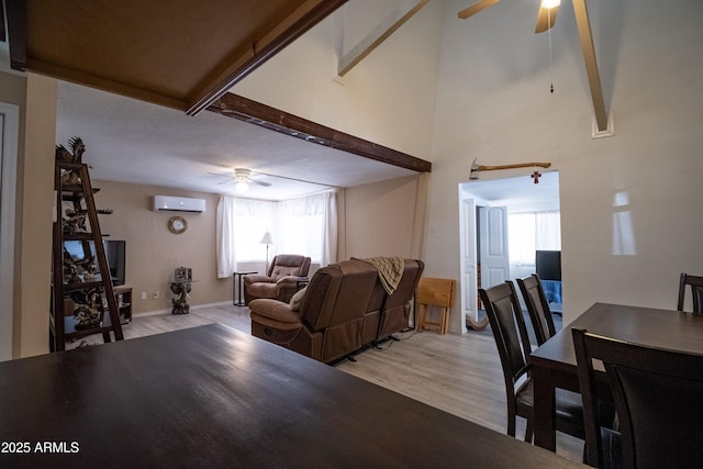 living room featuring light wood-type flooring, an AC wall unit, ceiling fan, and a towering ceiling