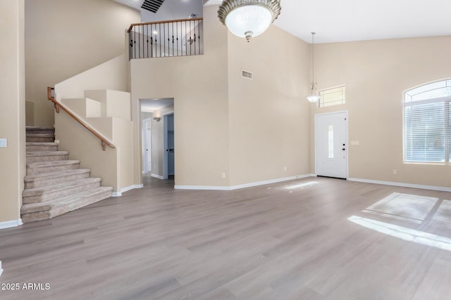 unfurnished living room with a towering ceiling and hardwood / wood-style flooring